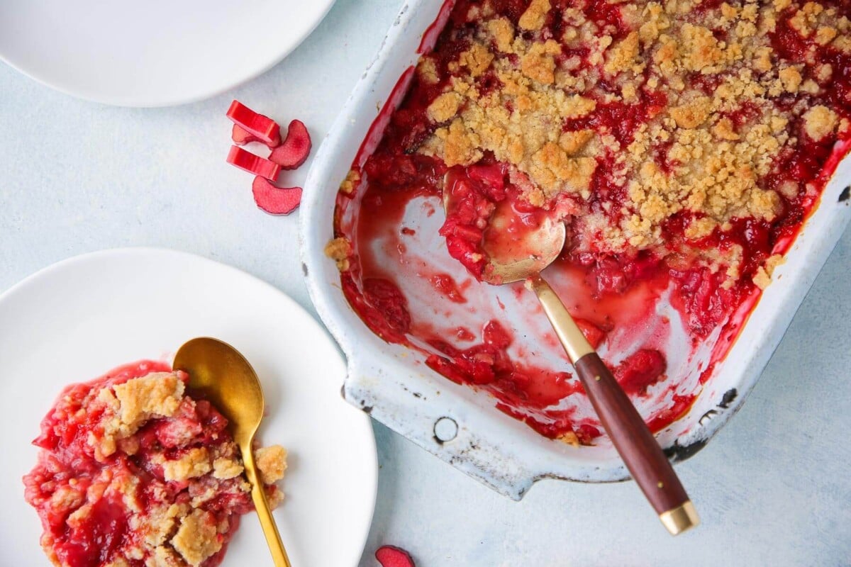 Golden spoon resting in strawberry rhubarb crumble with bubbling fruit.