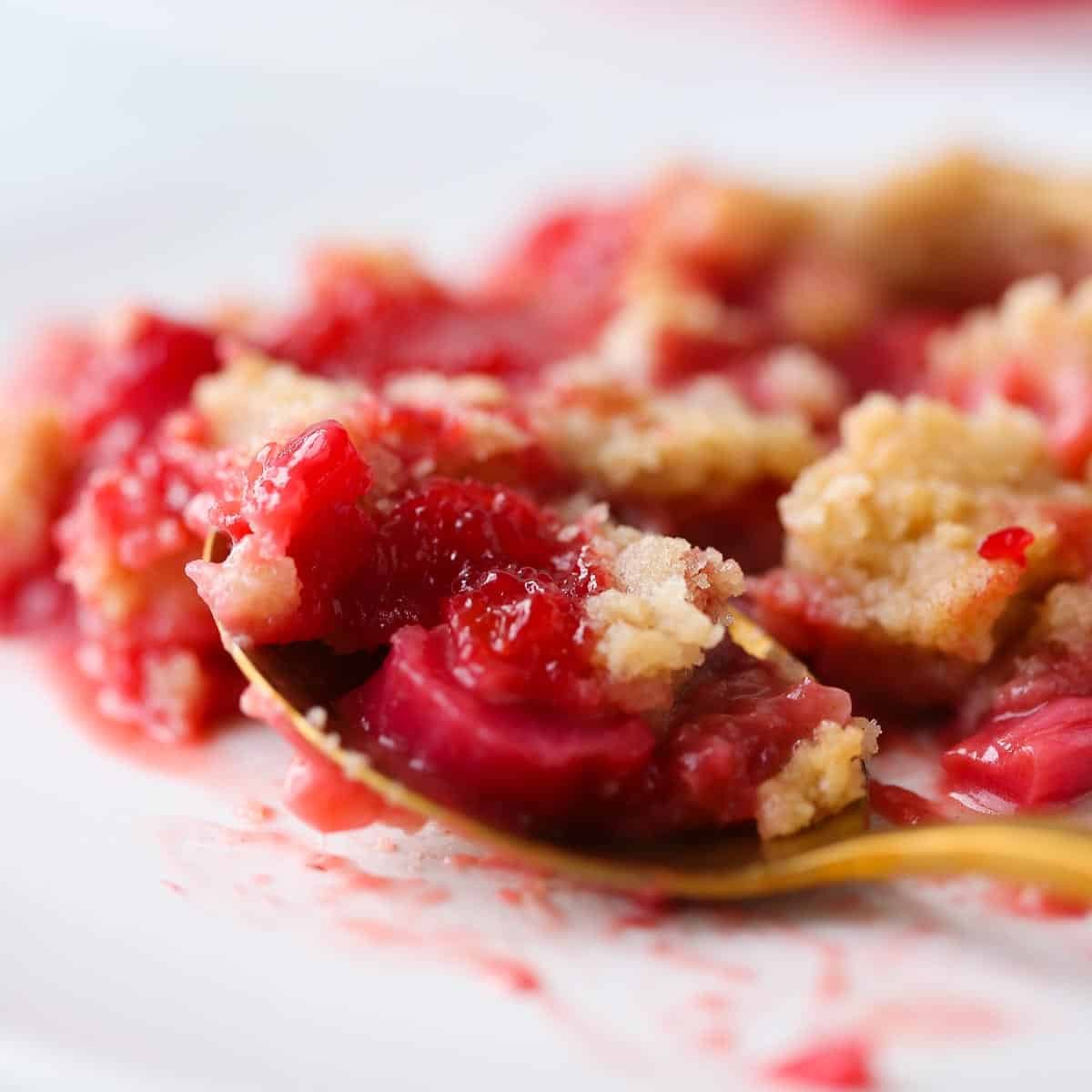 Close-up of juicy strawberries and rhubarb baked under golden crumble topping.