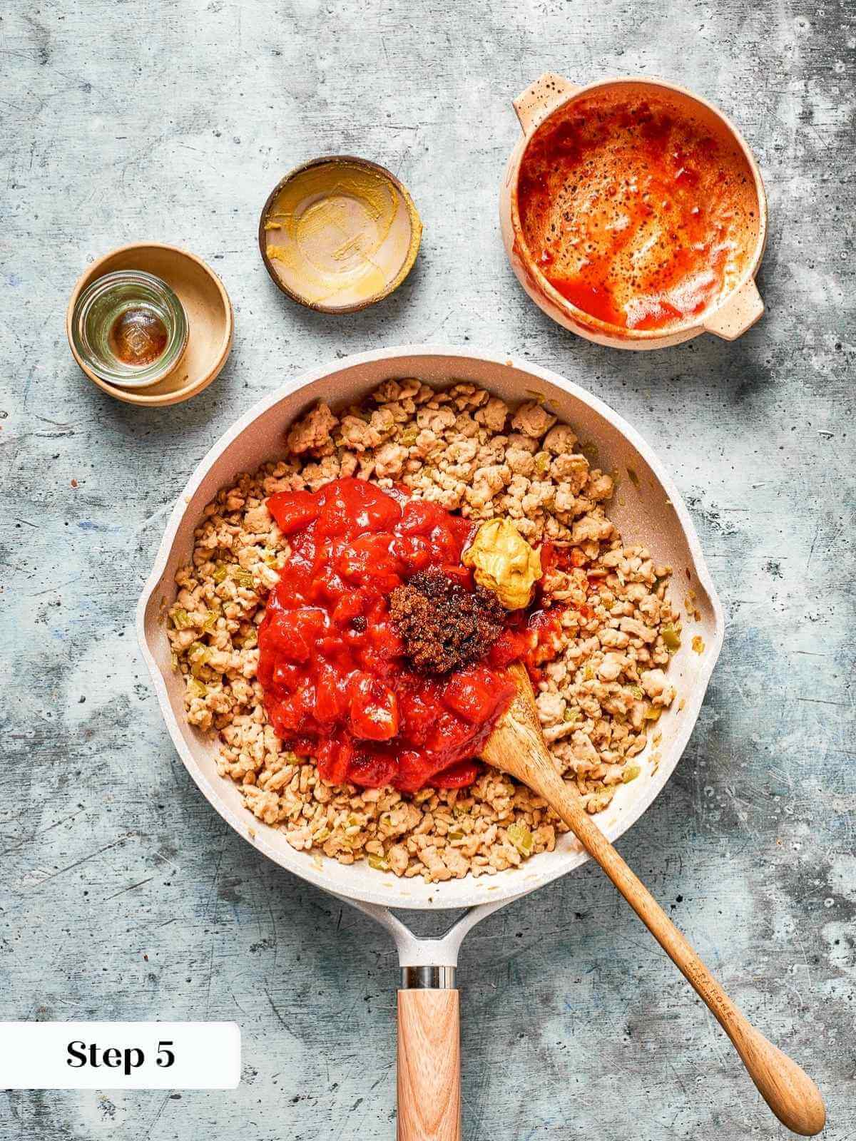 Pouring in sauce ingredients for sloppy joes over cooked meat.