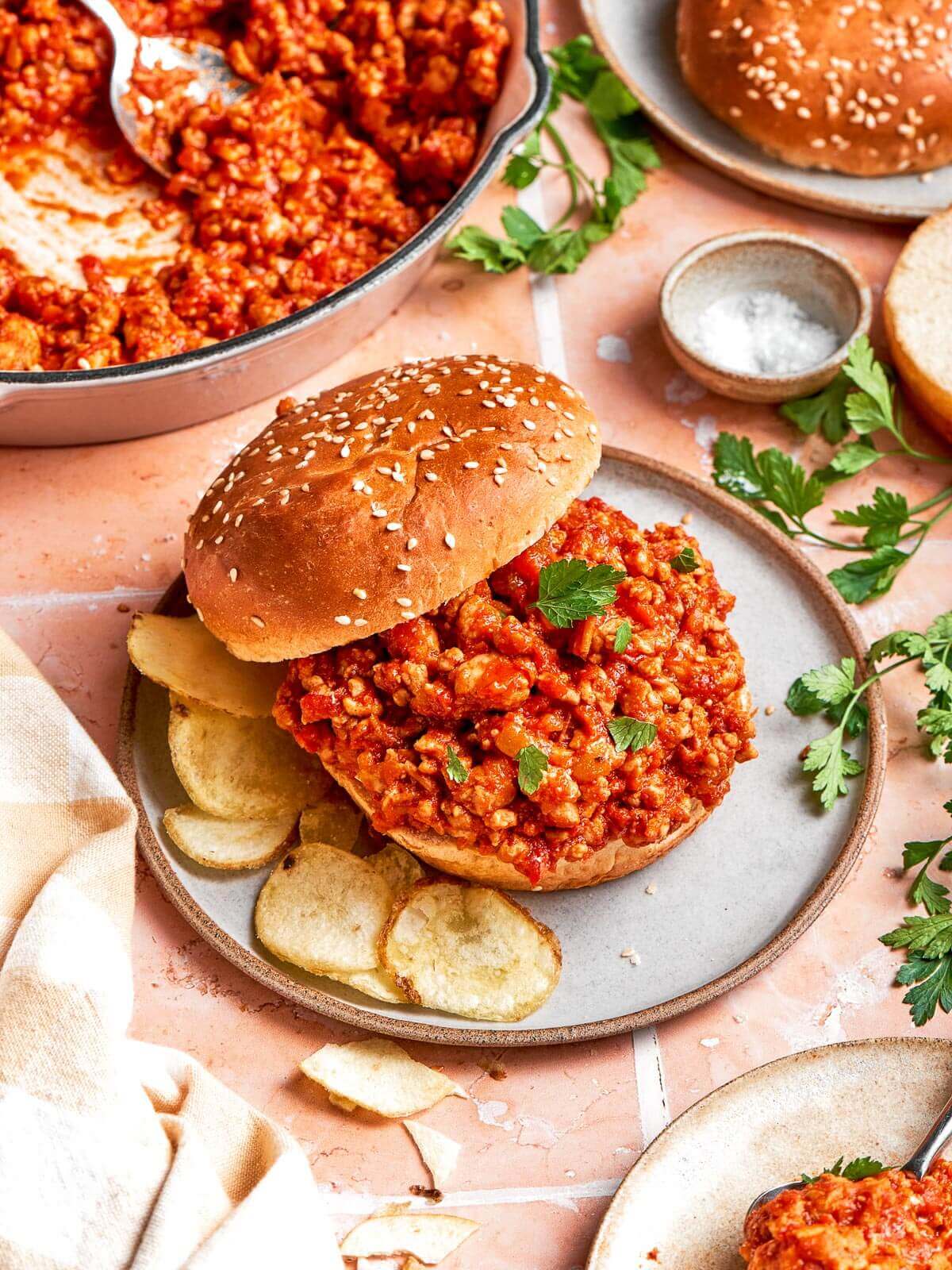 Sloppy joe sandwich plated with a side of potato chips.