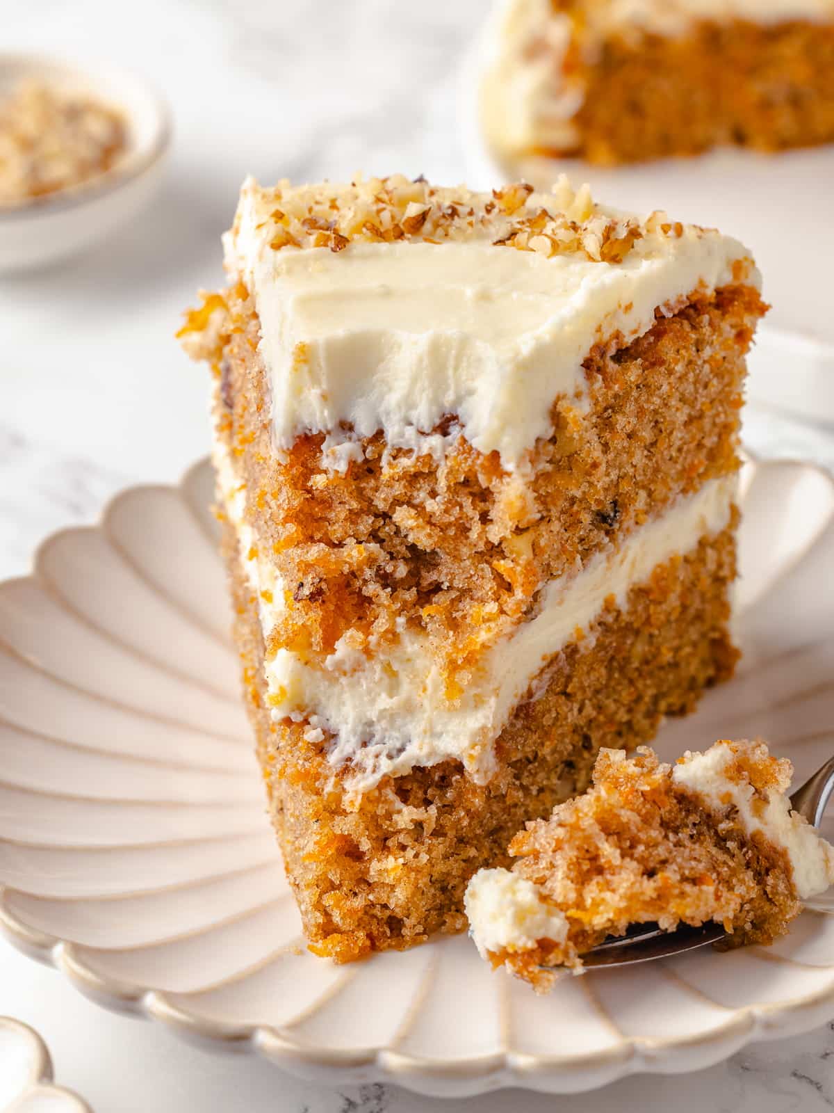 Forkful missing from a slice of carrot cake.