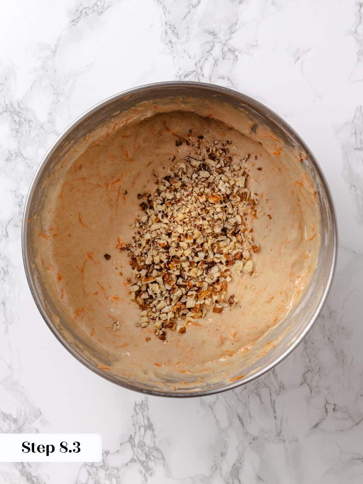 Toasted walnuts being folded into carrot cake batter.