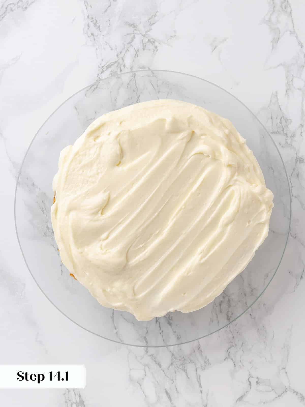 First cake layer covered in cream cheese frosting.