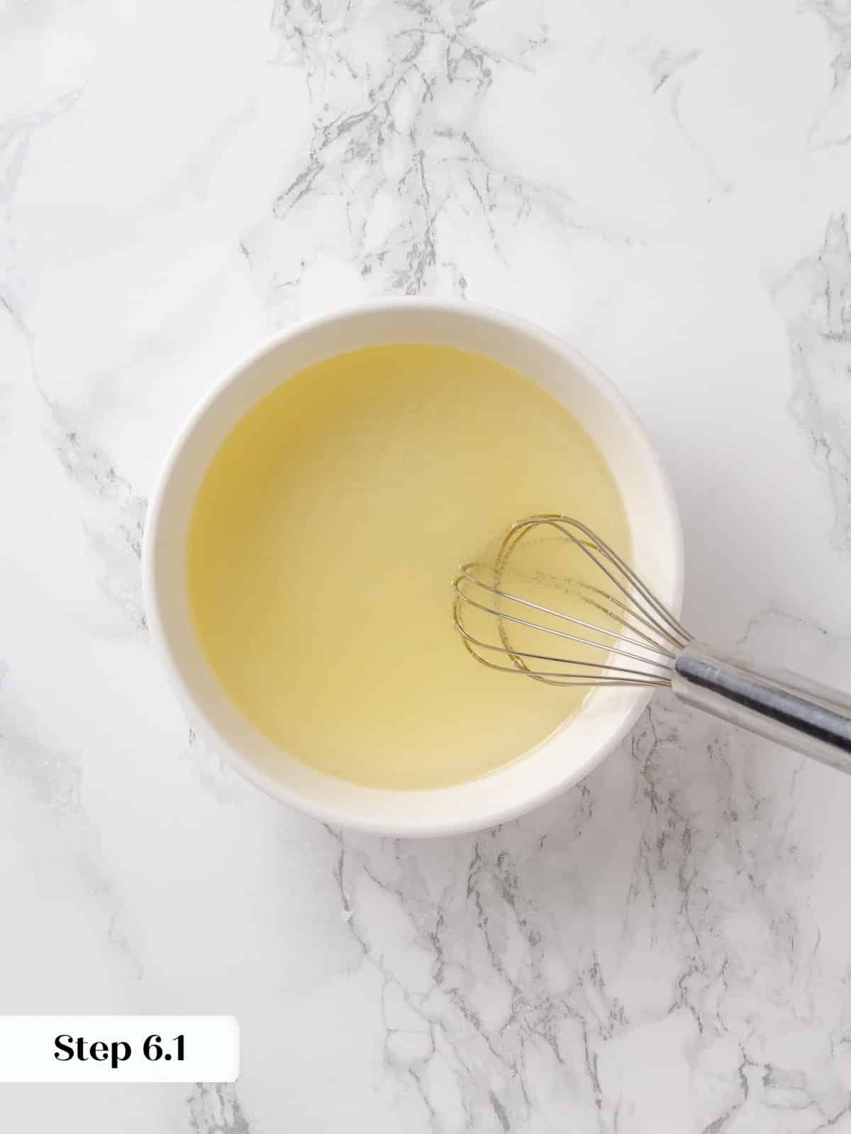 Whisking oil and lemon juice together in glass.