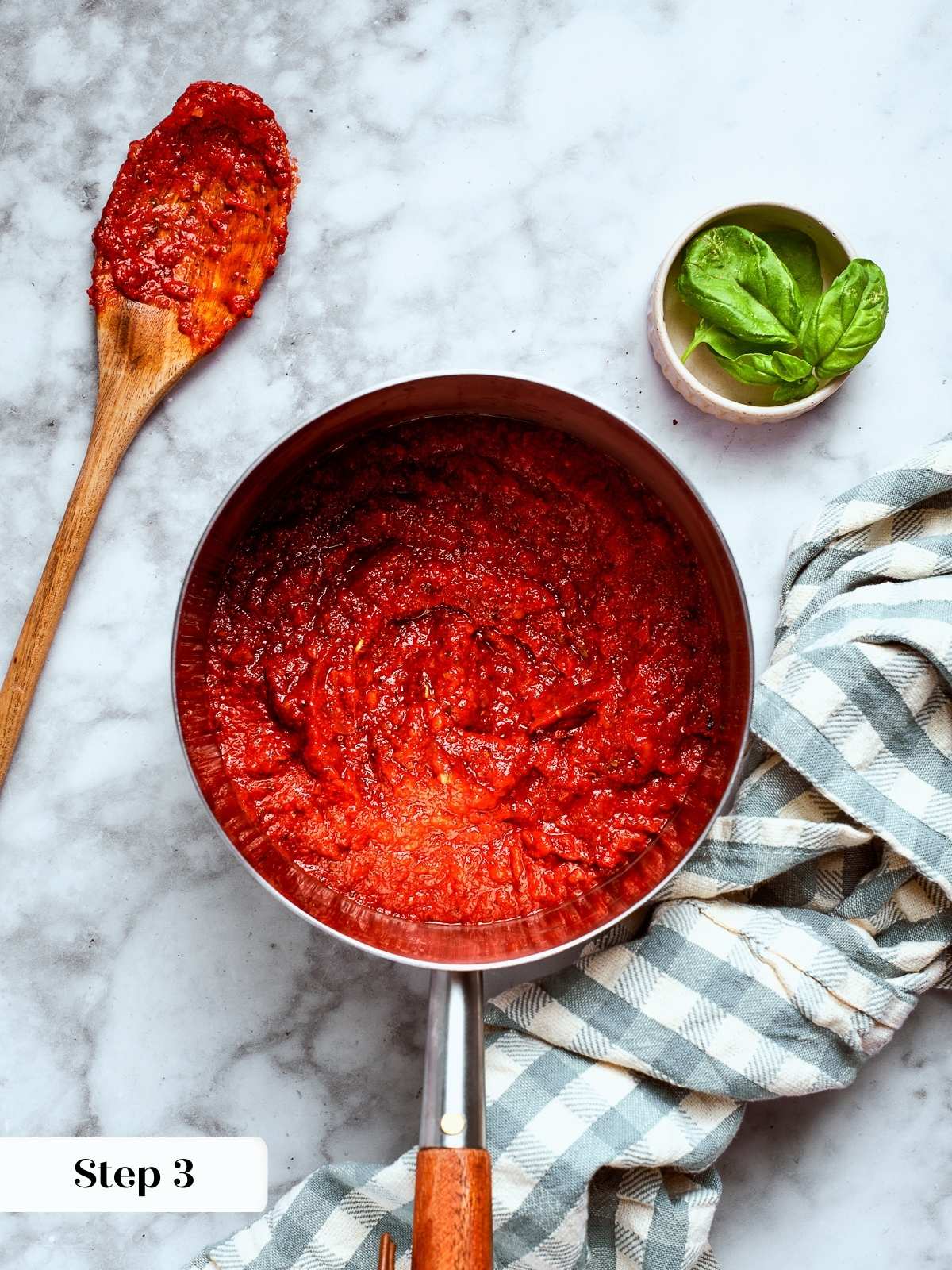A small spoonful of sauce next to a saucepan for tasting.