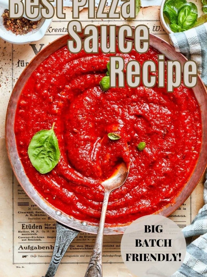Fresh basil leaves next to a pan of cooked sauce.