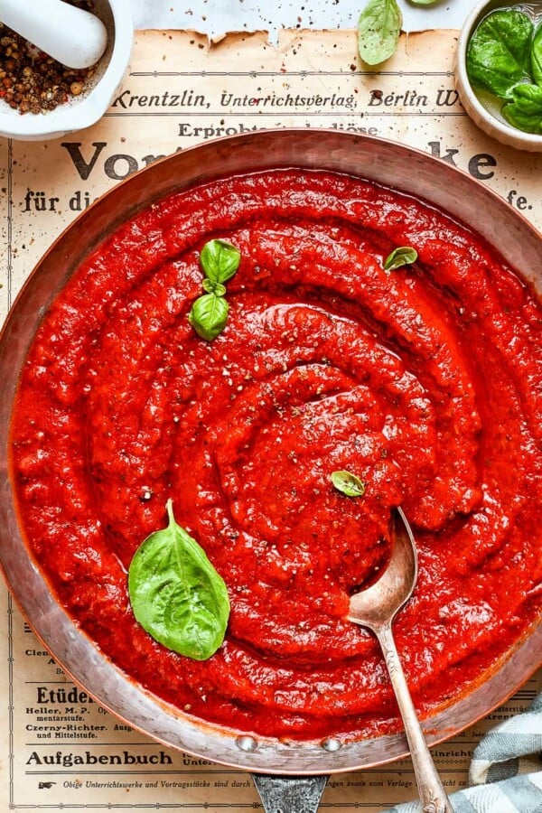 Seasoned sauce flecked with herbs and black pepper in a saucepan.
