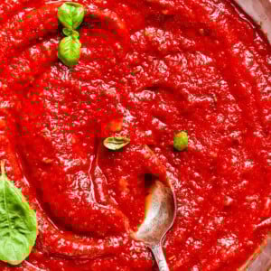 Rich tomato sauce clings to a spoon, ready to top a fresh crust.