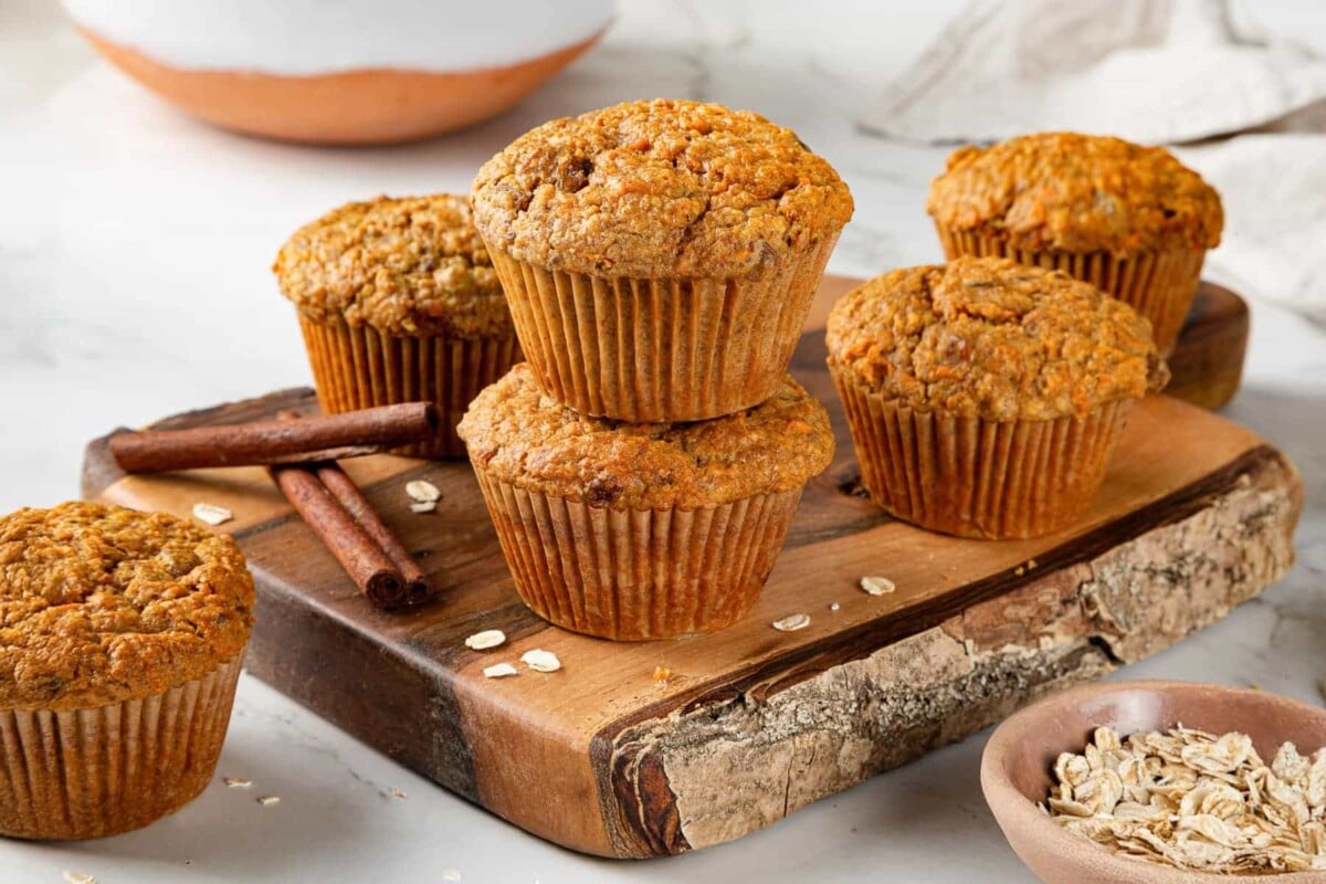 Group of carrot muffins displayed on a wooden cutting board.