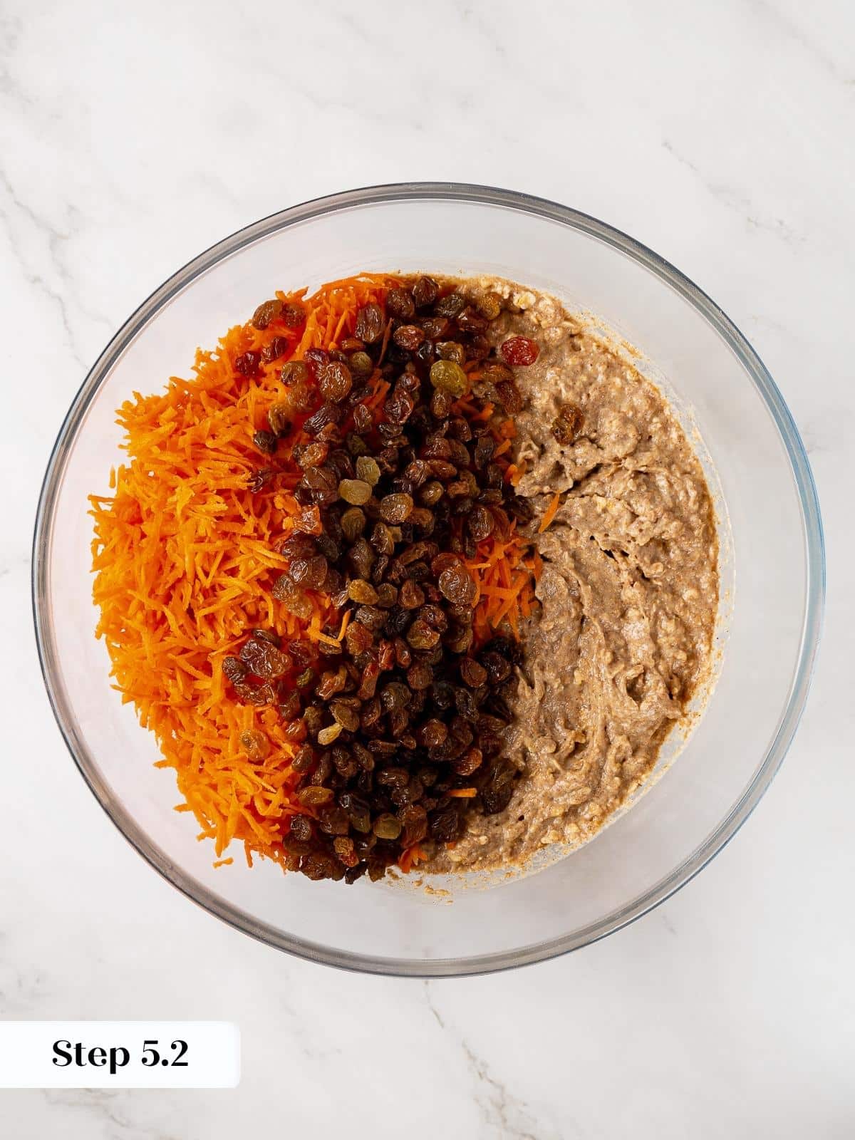Raisins and grated carrots being folded into muffin batter.