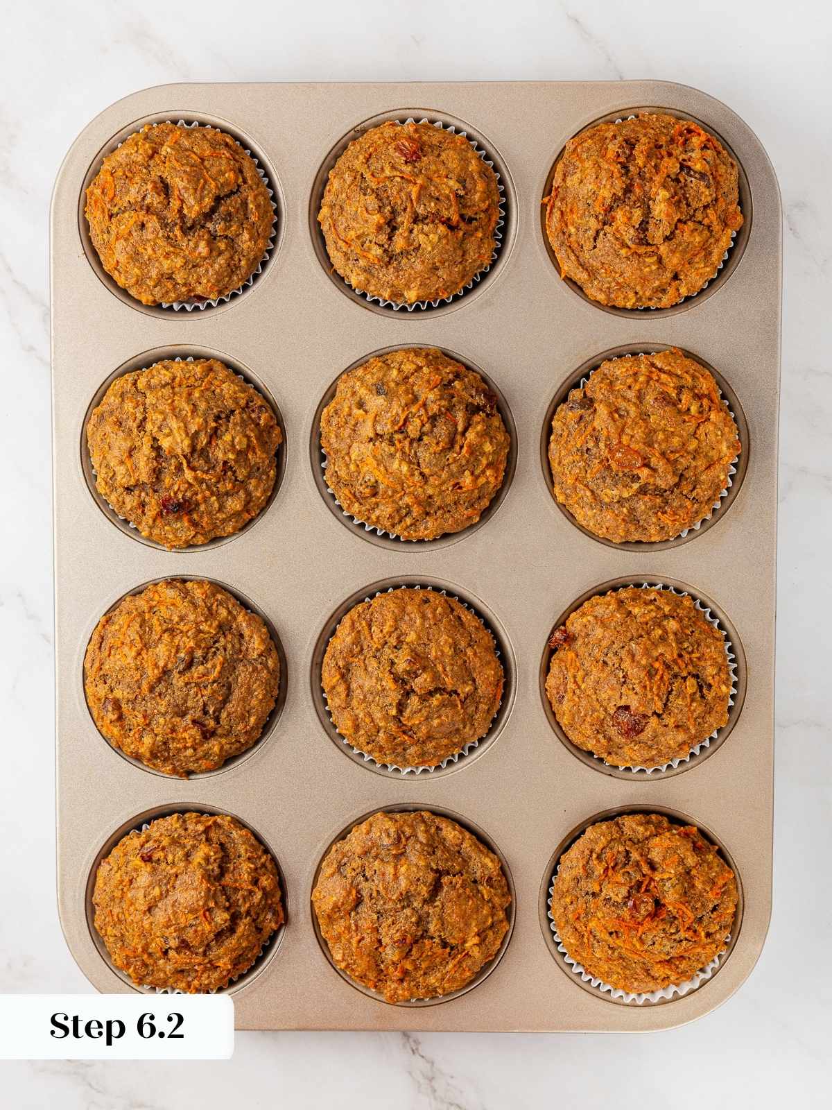 Freshly baked carrot muffins in a muffin pan just out of the oven.