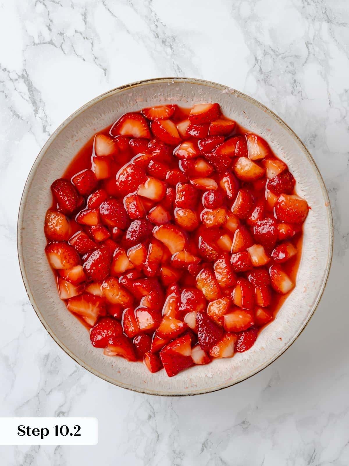 Macerated strawberries releasing juices in a glass bowl.