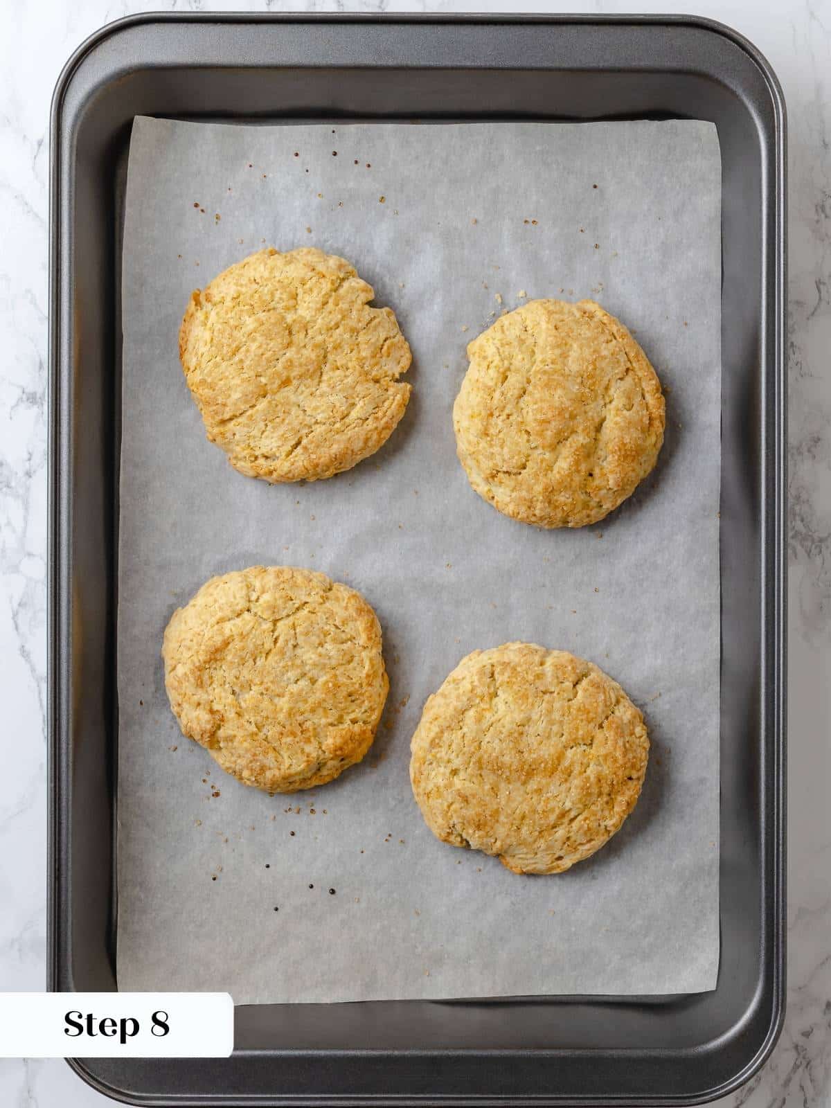 Baked shortcakes on a parchment-lined sheet, golden and crisp.
