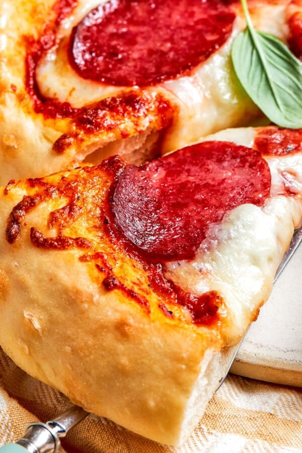 A cheesy slice of pepperoni pizza lifted with a server.