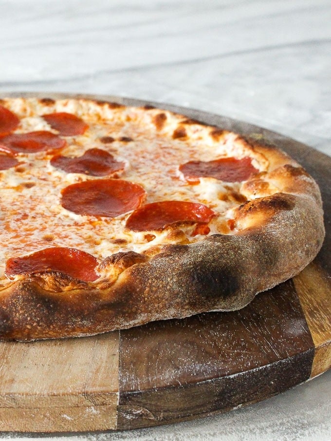 Finished sourdough pizza served on a rustic wooden board.