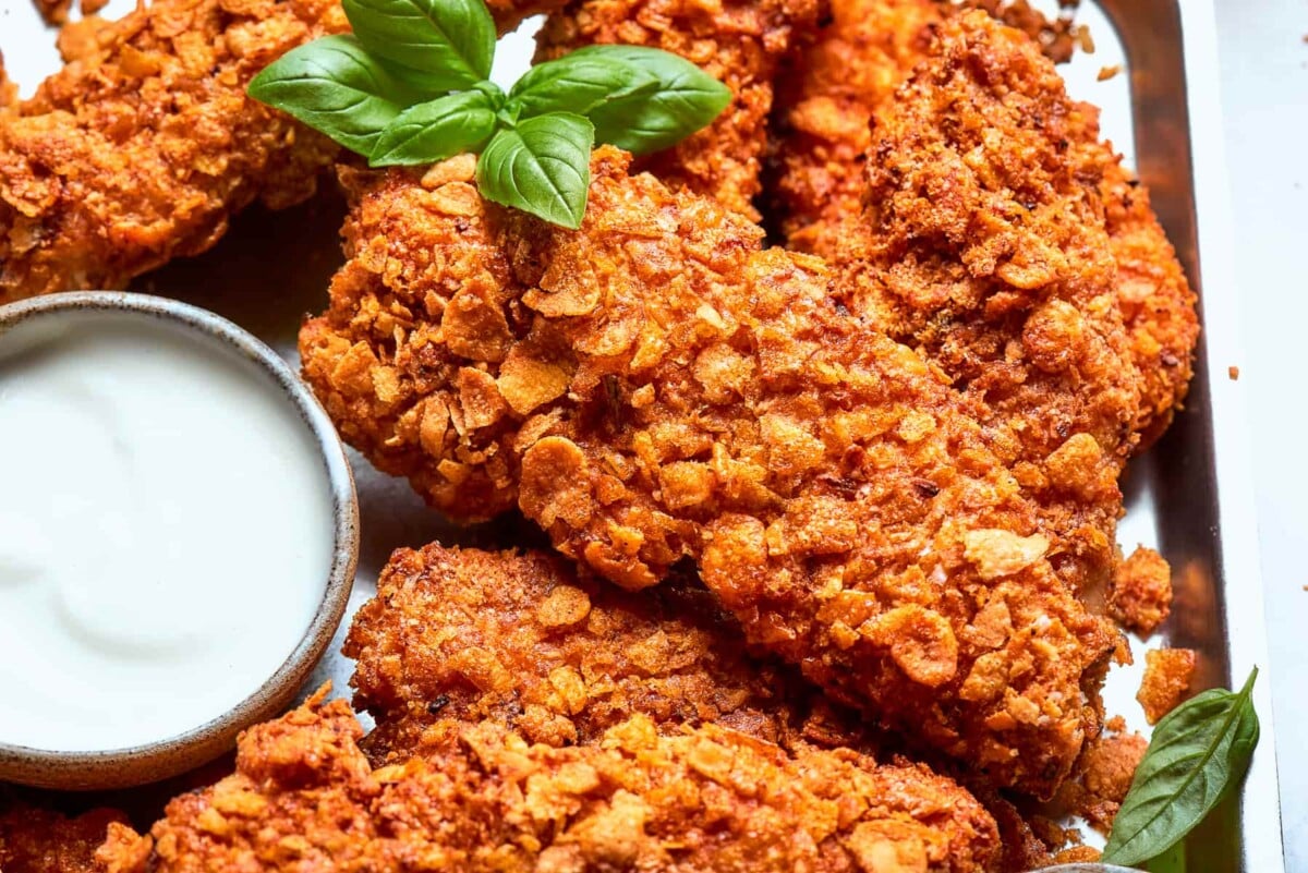 Finished chicken tenders garnished with fresh basil leaves for color and flavor.