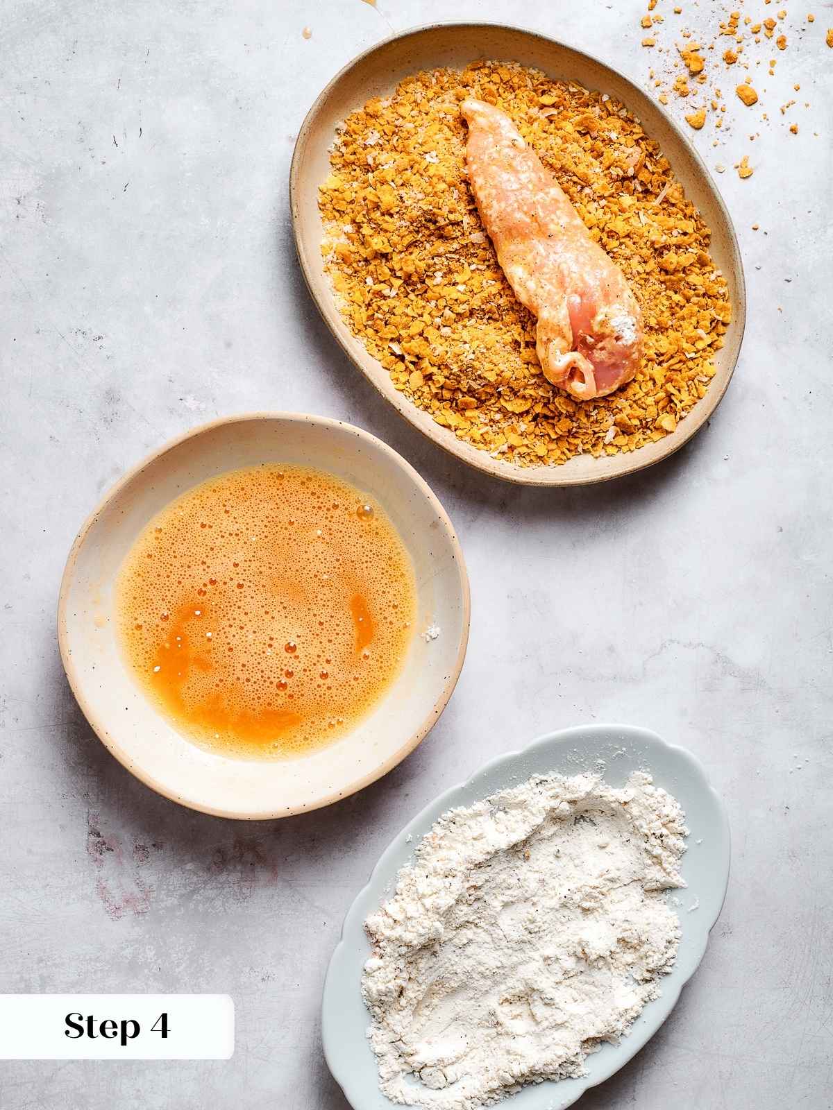 Chicken tenders being pressed into chex and breadcrumb coating before air frying.