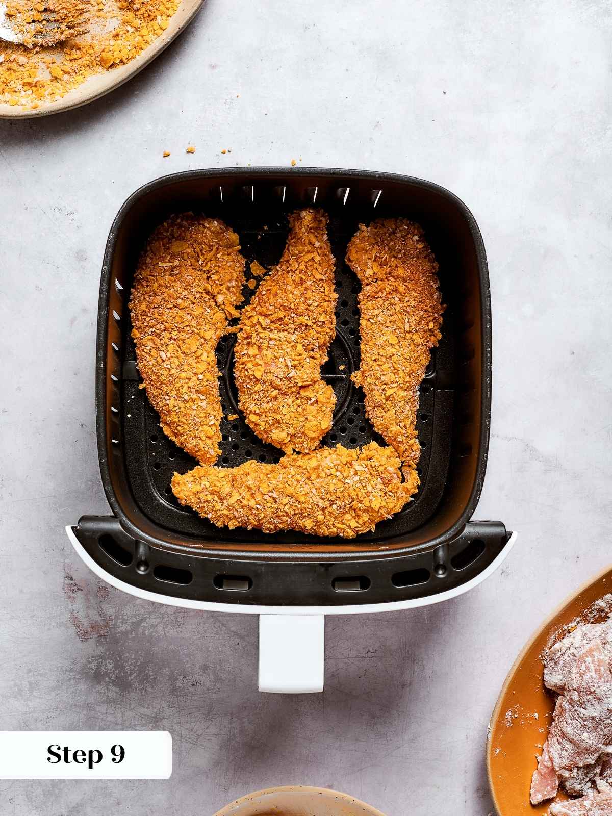 Chicken tenders lined up in air fryer ready to cook to golden crispness.