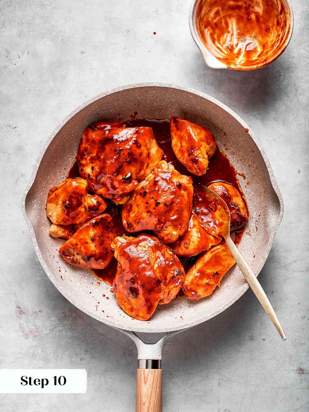 Chicken coated in thick red gochujang sauce after simmering in a pan.