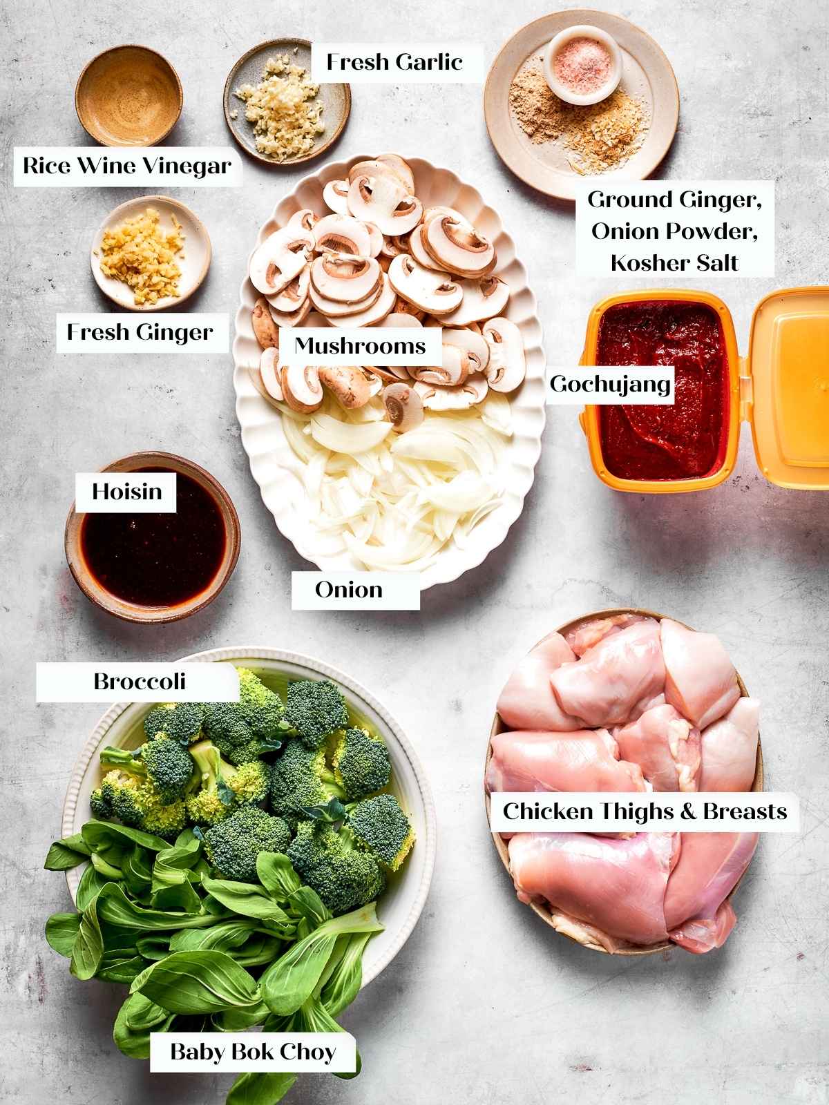 Raw ingredients including chicken, bok choy, mushrooms, garlic, and gochujang laid out on counter.