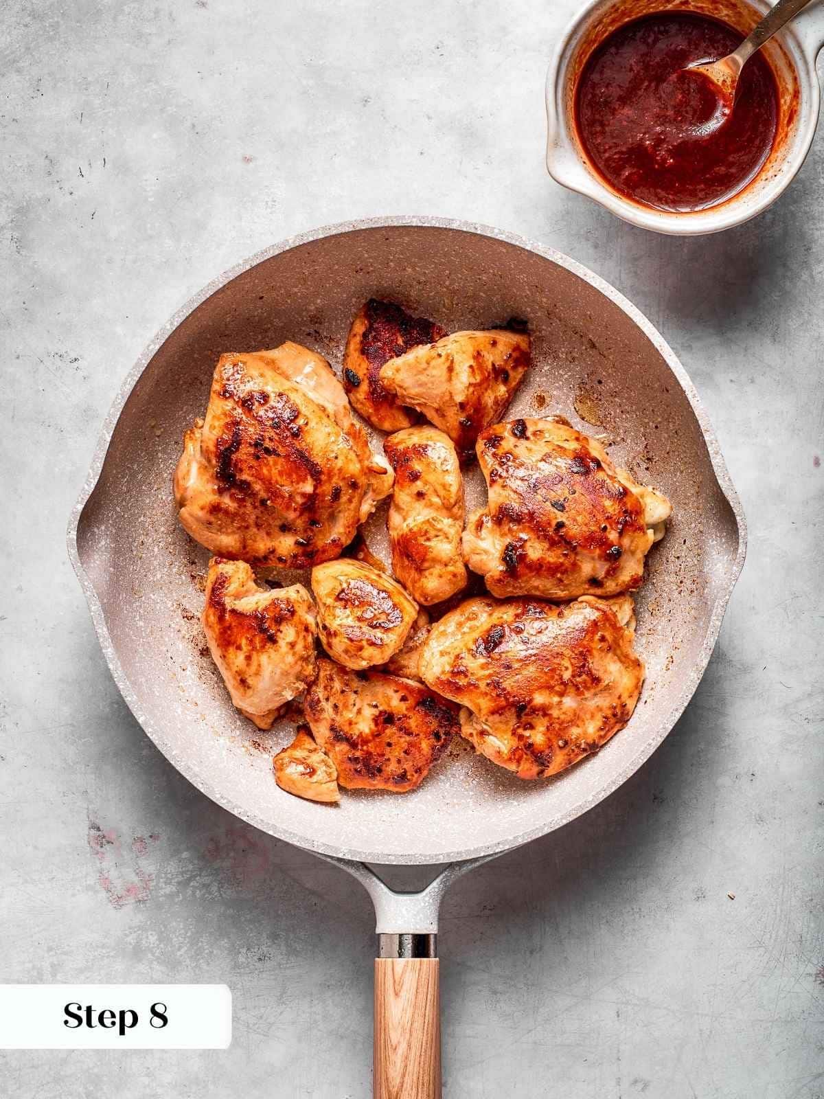 Chicken browning in a skillet before adding gochujang sauce, showing crispy golden sear.