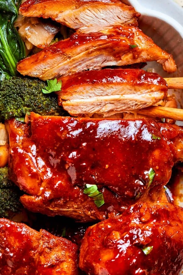 Thick gochujang sauce coating pan-seared chicken pieces with mushrooms in a bowl.