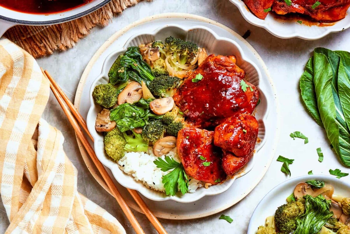 Gochujang chicken served with vegetables and rice on a white table with natural light.