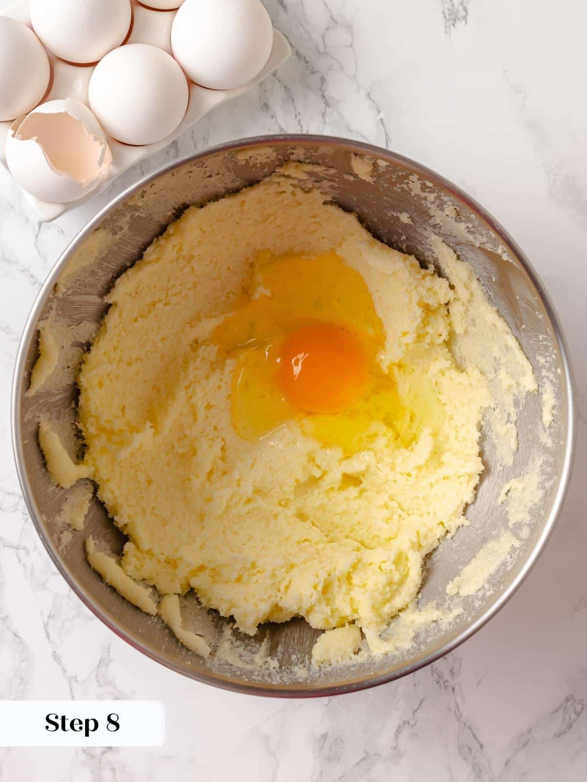 Eggs being added one at a time into the creamed butter and sugar mixture.