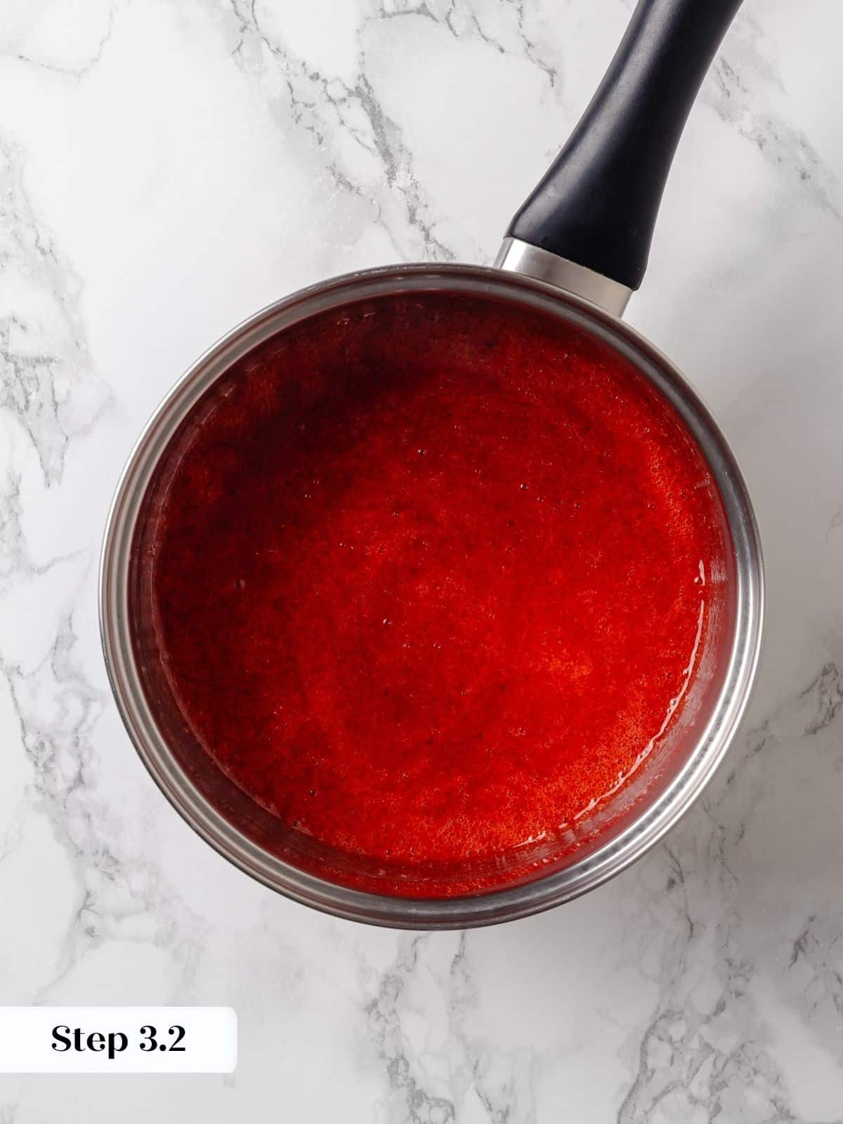 Strawberry jam finished cooking, thickened and glossy in the saucepan.
