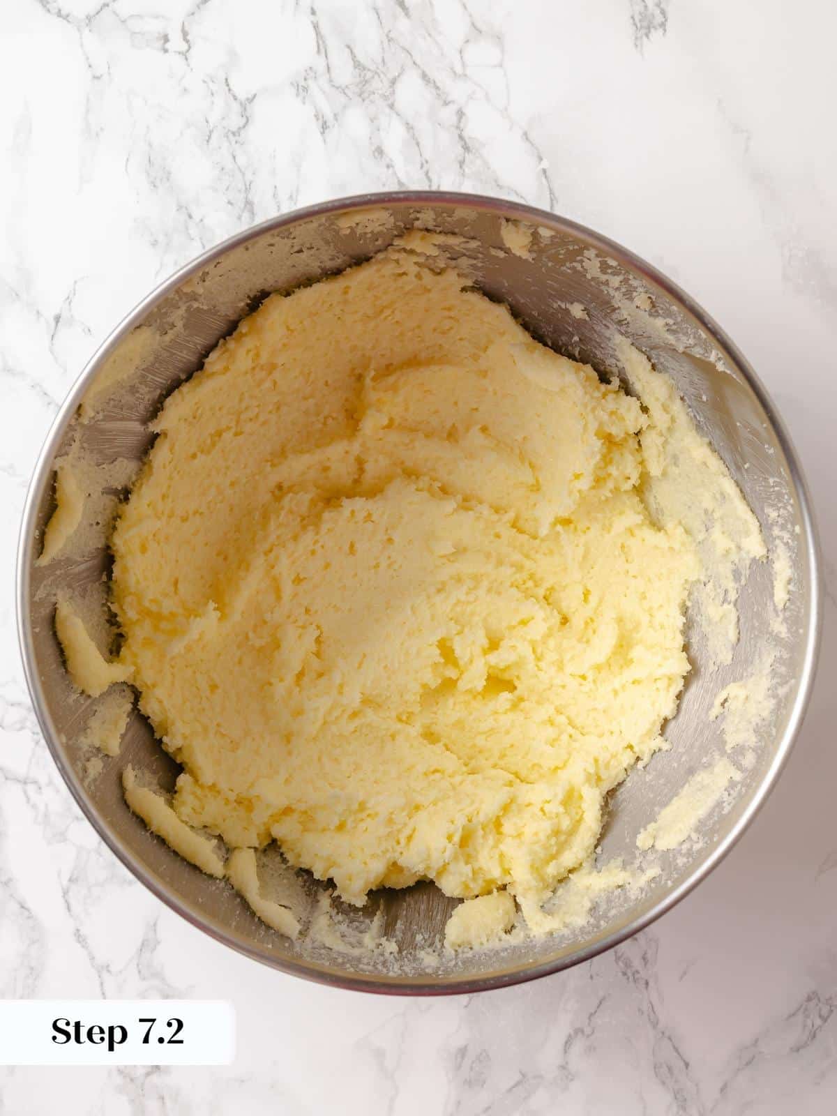 Butter and sugar beaten into a thick, pale paste in a mixing bowl.