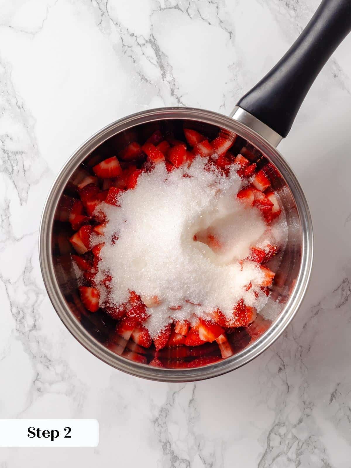 Fresh strawberries, sugar, and lemon juice mixed together in a pot for jam.