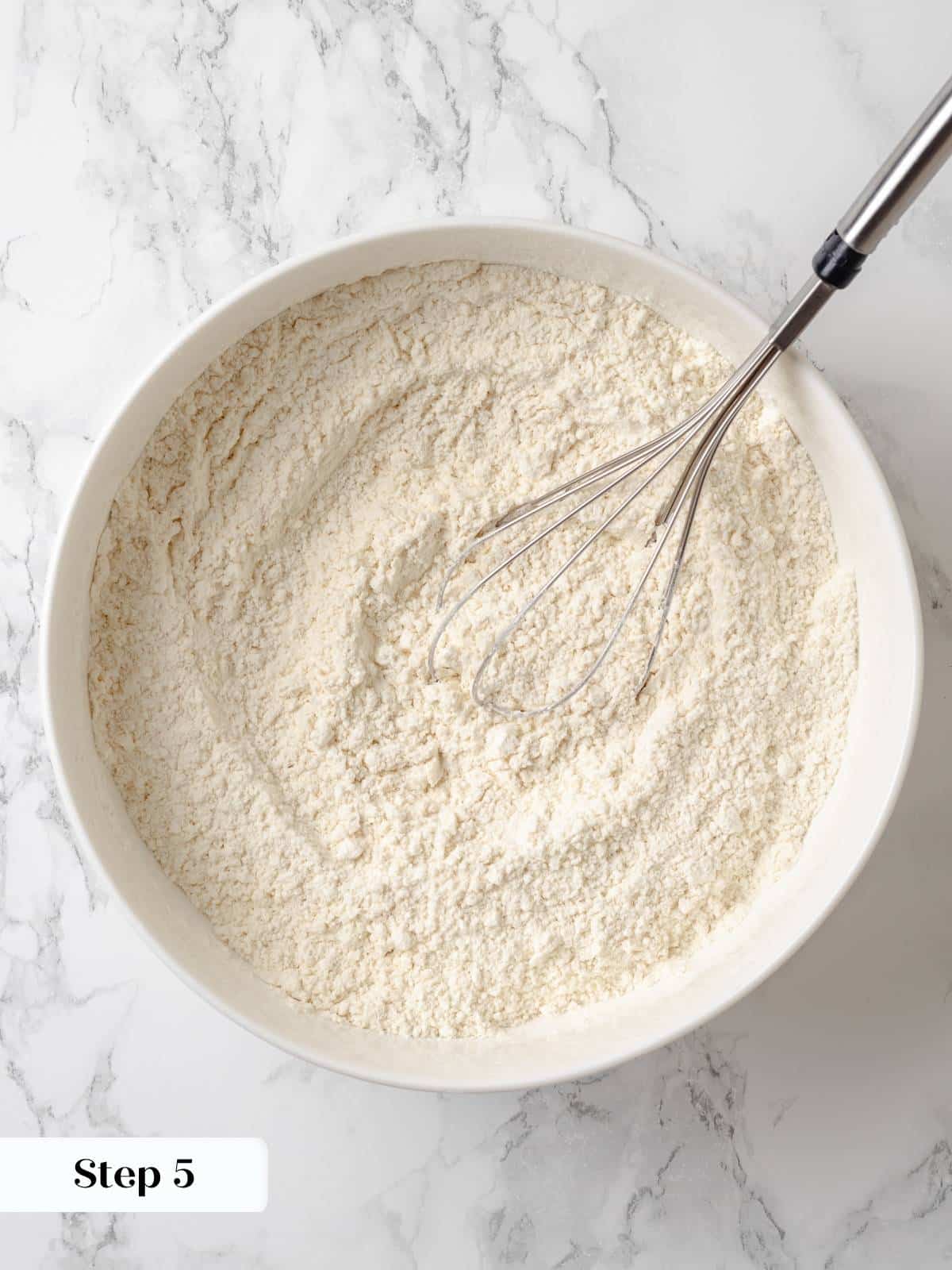Whisking flour, salt, and baking soda together in a large bowl for even mixing.