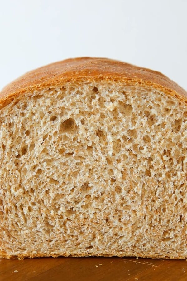 A partially cut loaf of whole wheat sandwich bread, showing a soft inside.