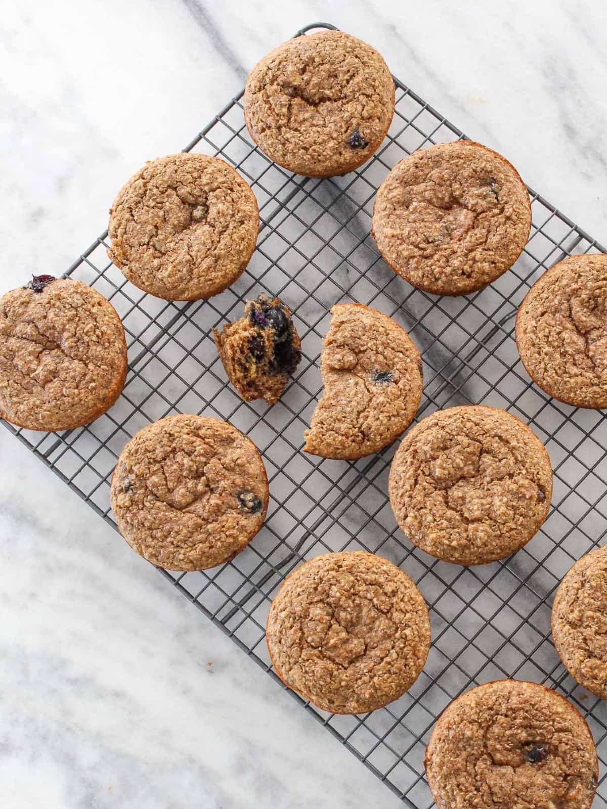 Banana muffins on a cooling rack placed on a white marble backdrop, perfect for meal prep or snacking anytime.