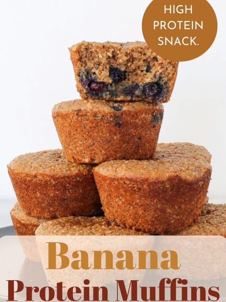Fresh banana muffins bursting with blueberries and fiber-rich grains stacked.