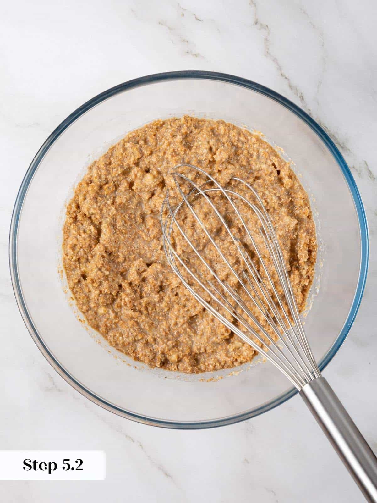 Wet ingredients including mashed banana, oil, and eggs mixed together until smooth for muffin batter.