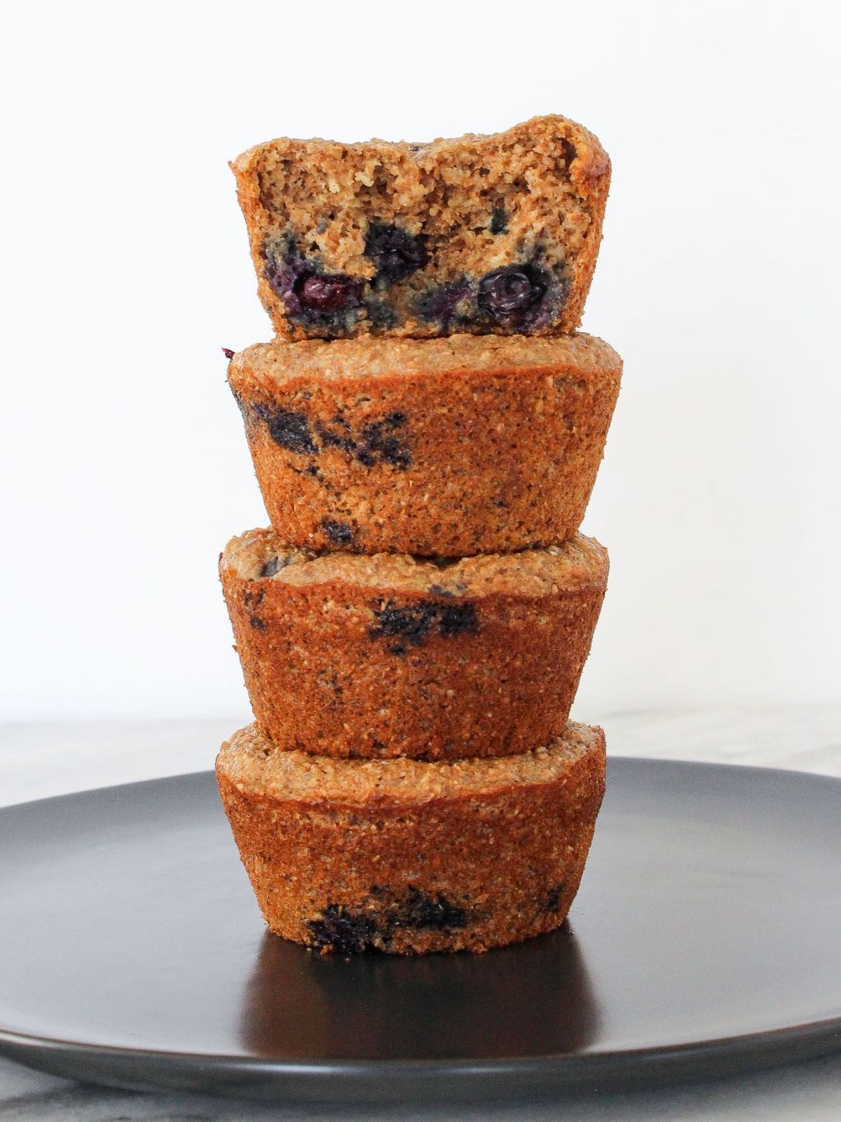 Freshly baked banana muffins stacked neatly on a grey plate, ready for breakfast or meal prep.