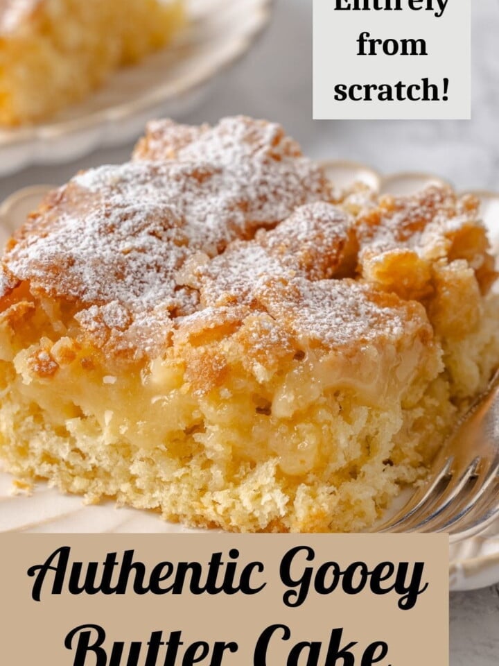 A square of gooey butter cake on a plate dusted with powdered sugar and golden edges.