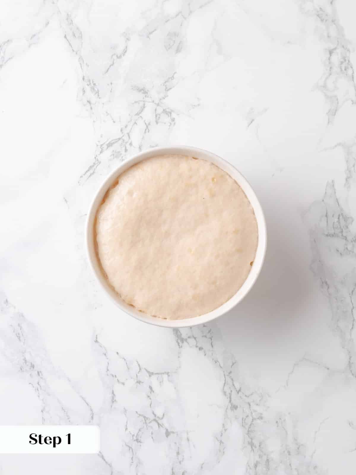 Yeast has foamed in warm water and milk, showing it's activated and ready.