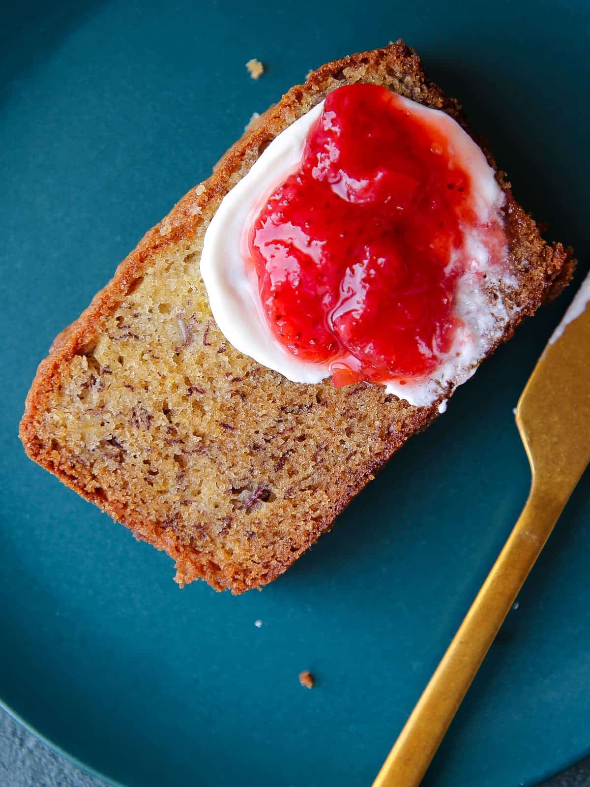 Thick slice of moist banana bread served on a vibrant blue ceramic plate.