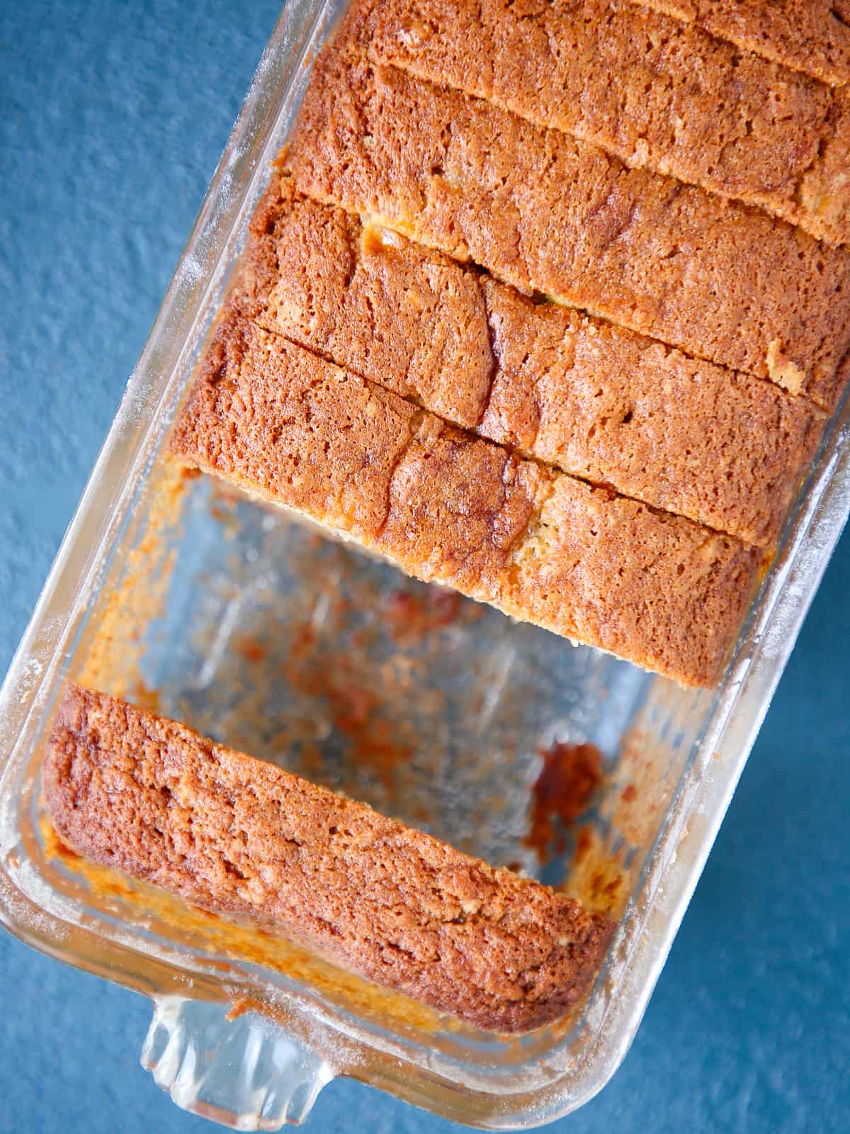 Loaf of banana bread still in the baking dish with visible browning around the edges.