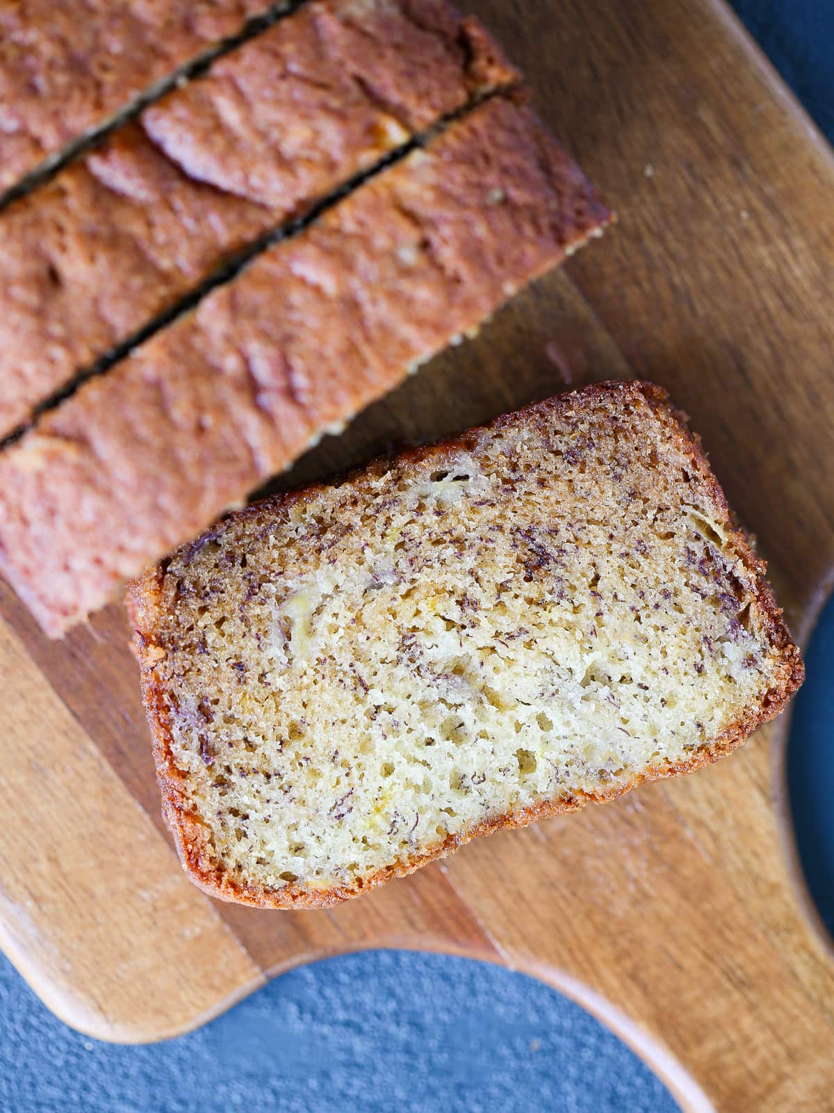 Banana bread sliced on a wooden cutting board.