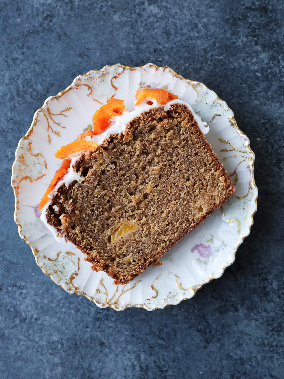 Single slice of peach cake on a plate, showing soft crumb and golden edges.