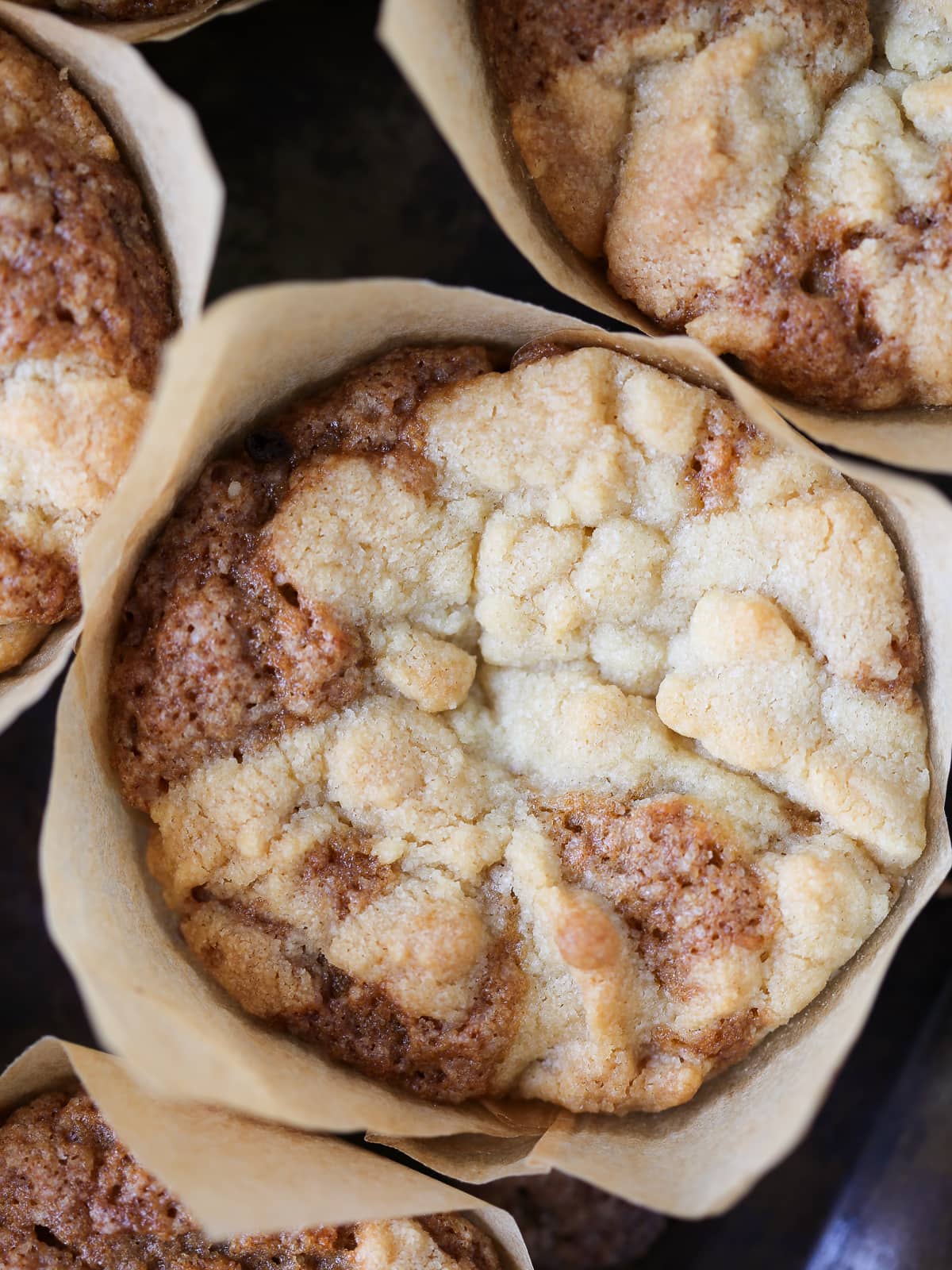 A single peach muffin topped with crumbly brown sugar streusel and visible peach pieces.