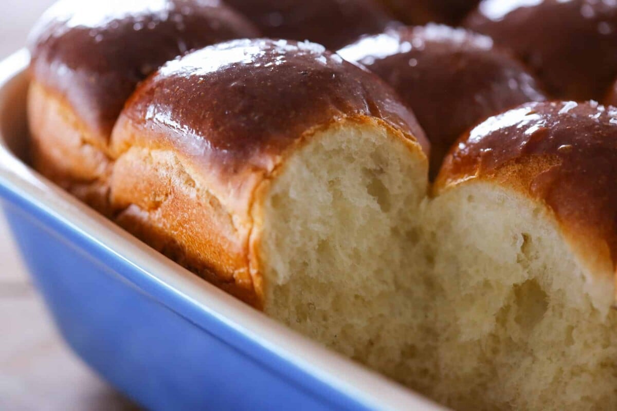 Potato rolls nestled together in a blue ceramic baking dish.