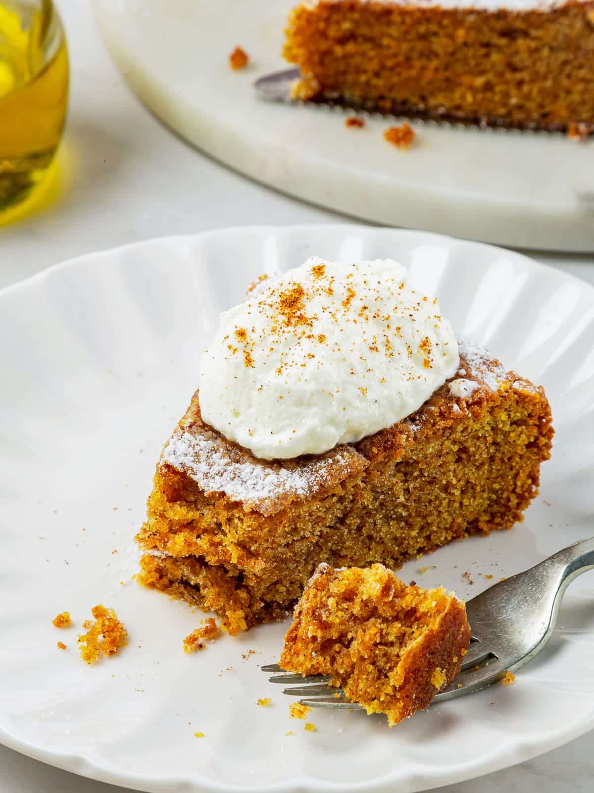 A slice of pumpkin cake with a bite taken, showing its soft and tender center.