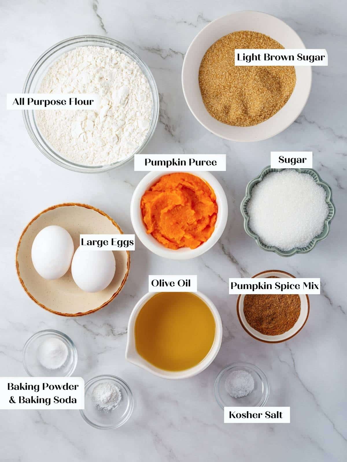All ingredients for pumpkin olive oil cake measured out on the counter in small bowls.