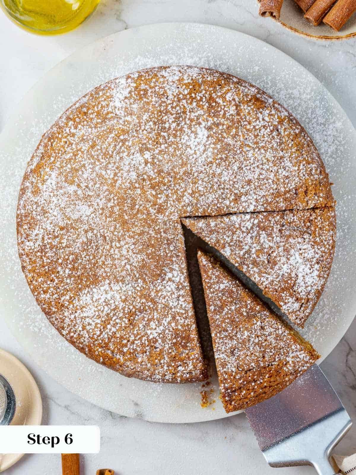 A fine layer of sugar coats the pumpkin cake surface after sifting, adding final visual touch.