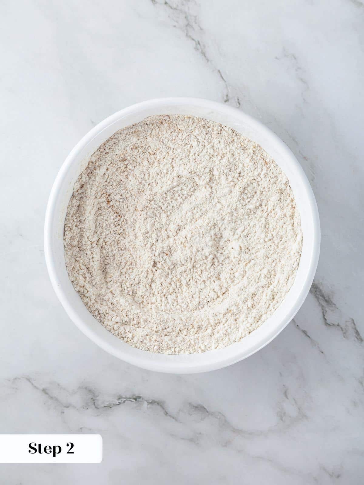 Pumpkin spice mix, flour, and salt are combined with a whisk before folding into wet ingredients.