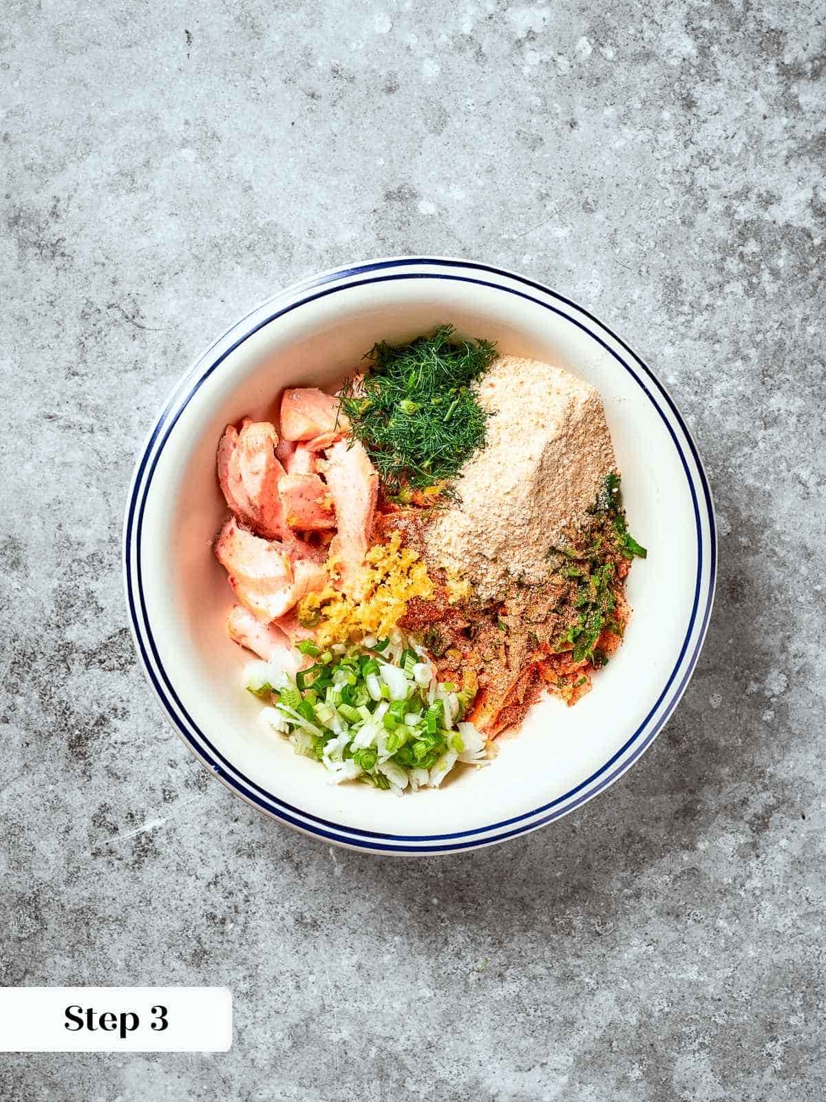 Mixing bowl filled with salmon, herbs, and seasoning before adding the egg.
